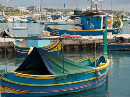 Various fishing boats are moored in the harbour, standing in calm waters, many colourful fishing