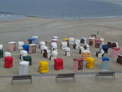 Many colourful beach chairs on the beach, the sea in the background and a cloudy sky, beach chairs
