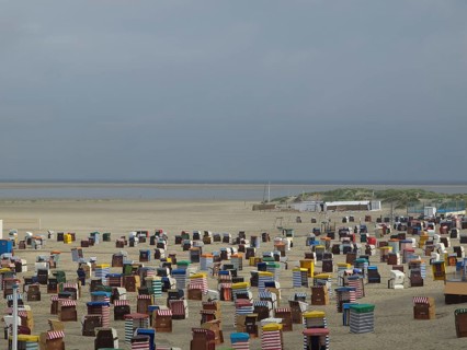 Numerous colourful beach chairs are located in large numbers on the empty beach with a wide view of