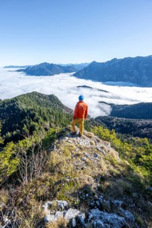 Mountaineer on the rocky summit of the Ettaler Manndl, view over mountain landscape and sea of