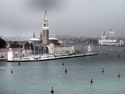 A view of the church and marina of Venice with boats in the water on a cloudy day, church towers