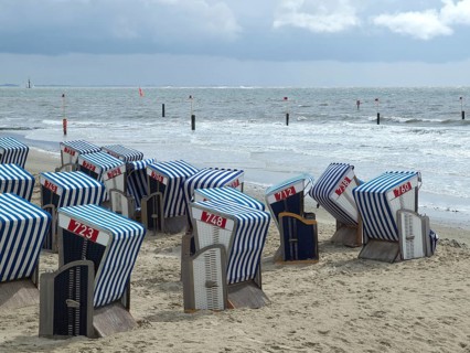 Blue and white beach chairs on a sandy beach with a view of the sea and a cloudy sky, blue and
