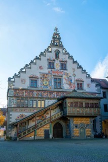 Detailed view of a historic building with frescoes and a bay window under a clear blue sky, Lindau