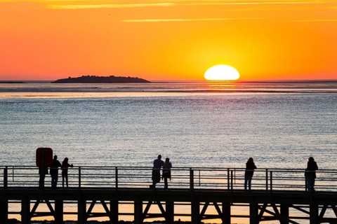 Silhouettes of several people on the pier free canal, jetty, couples and individuals watch the