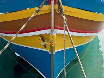 Colourful bow of a boat moored with ropes, on calm water in the harbour, many colourful fishing