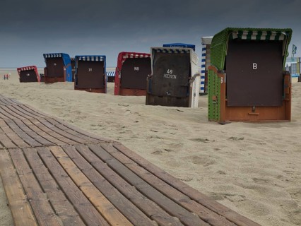 Beach chairs and a wooden jetty on the beach with a cloudy sky and a view of the sea, beach chairs