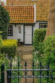 Small cosy house with red tiled roof and well-kept garden, old houses with green gardens in a small