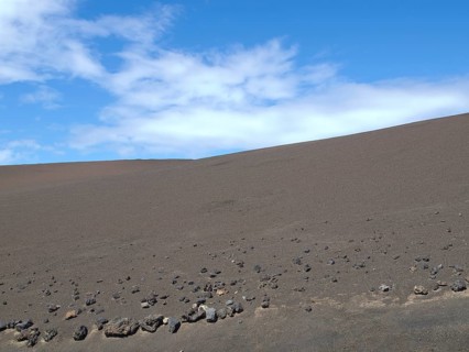 Vast desert landscape with blue sky and dry, stony ground, barren landscape of lava mountains,