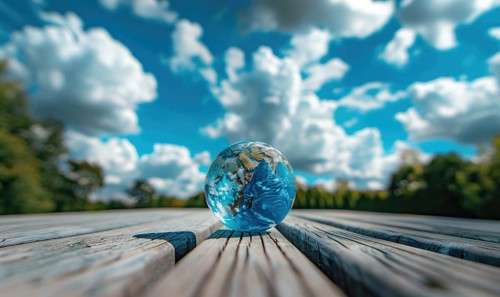An Earth globe placed on a wooden picnic table with a bright blue sky and fluffy white clouds AI