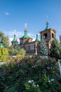 Flowers in front of the Russian Orthodox Church Cathedral of the Holy Trinity, wooden church with