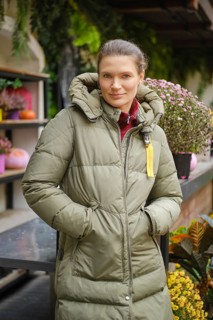 Cheerful woman stands at a display case with potted flowers at autumn flower fair