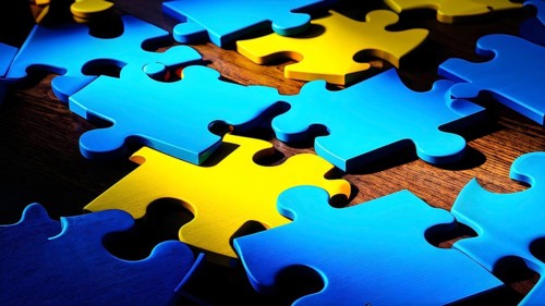 Illustration of scattered blue and yellow puzzle pieces sprawled across as a wallpaper background,