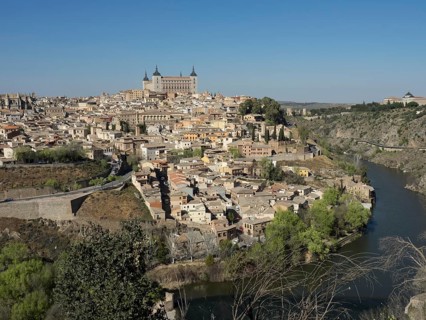 Wide view of a historic city on a river with characteristic church towers and bridges, hills and a