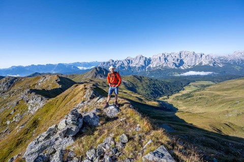Mountaineer on a grassy ridge, mountain panorama, view of rocky mountain peaks of the Sesto