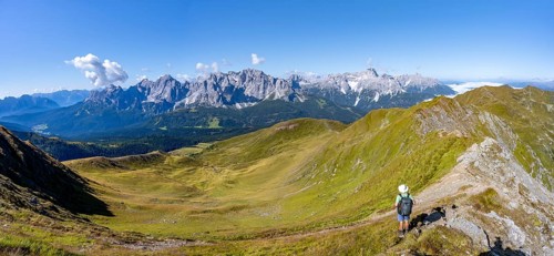 Mountaineers on a hiking trail between green mountain meadows on a mountain ridge, mountain