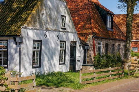 Traditional old houses in a village, surrounded by trees and a wooden fence in the sunlight,