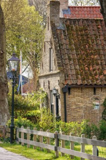 Historic house with tiled roof, fence and street lamp, surrounded by trees in spring, historic