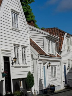 Narrow alley with white wooden houses with red tiled roofs and flowering plants, white wooden