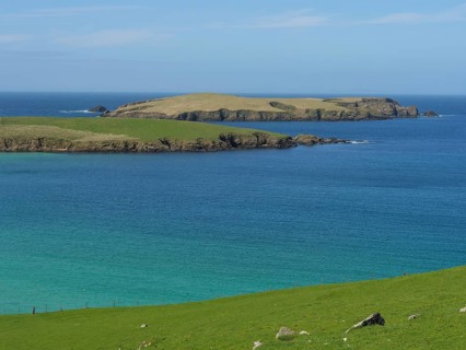 Peaceful island in the blue ocean with green grassland and blue skies. The atmosphere is calm and