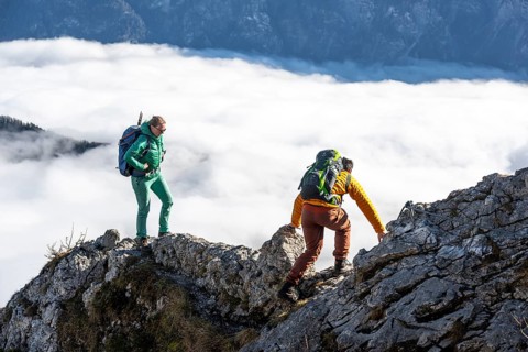 Two hikers at Ettaler Manndl, view over mountain landscape and sea of clouds, high fog in the