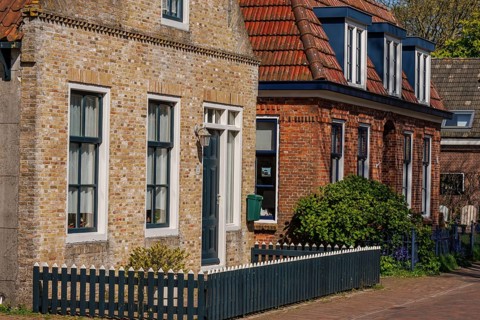 Row of houses with brick facades and white window frames along a quiet street, historic houses and
