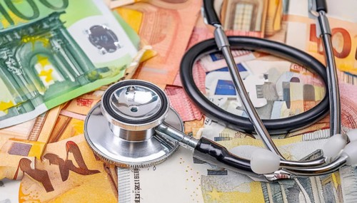 Symbolic photo of medical expenses, a stethoscope and medical instruments on a surface of euro