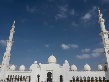 Large mosque with white domes, minarets and golden decorations under a blue sky, beautiful mosque