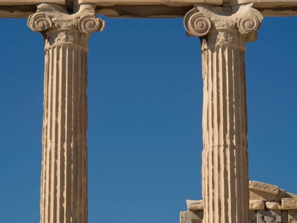 Close-up of ancient marble columns and their details against a clear blue sky, historical columns