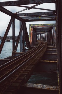 Rusty railway bridge with lake in the background. Cloudy day over Tauranga, New Zealand, Oceania