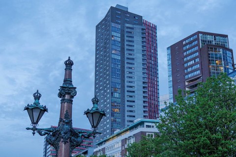 City view with modern skyscrapers and an old lamp post in the foreground under a blue sky, small
