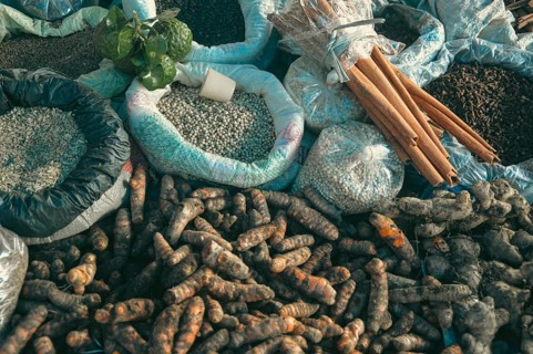 Assorted raw agricultural produce including cinnamon bark, lime, turmeric, clove, peppercorns and