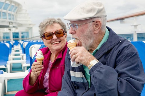 Happy senior adult couple enjoying ice cream on the deck of a luxury passenger cruise ship