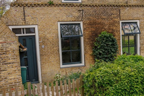 Quiet village life represented by a charming brick house with ivy-covered walls, old houses with