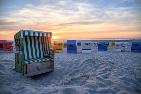 Colourful beach chairs on the beach at sunset, an open basket in the foreground, many colourful