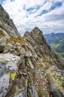 Narrow mountain path, rocky pointed summit of the Raudenspitze or Monte Fleons, with summit cross,
