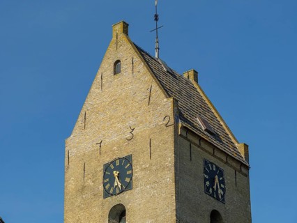 Brick church tower with two clock faces and blue sky in the background, church tower on stone with