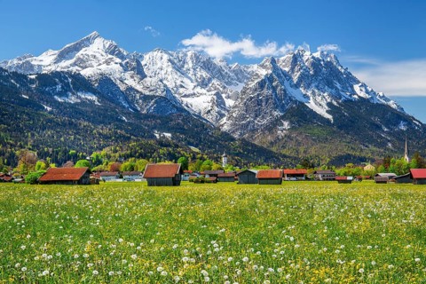 Spring meadow with hay barns at the edge of the village in front of Zugspitzgruppe 2962m in