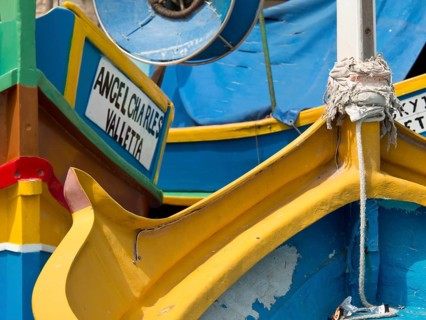 Colourful fishing boats in the harbour with different coloured details and a sign, many colourful