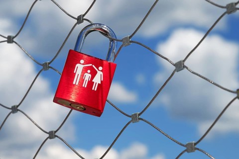 A single red love lock symbolising a family with a child hangs on a bridge railing over the Danube,