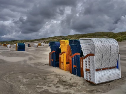 A composition of beach chairs in cloudy weather in a dune landscape, colourful beach chairs on the