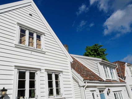 White wooden houses with windows and gutters under a clear blue sky in the sunshine, white wooden