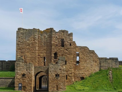 Close-up of a castle ruin with medieval architecture and a flag in the wind under a blue sky, ruins