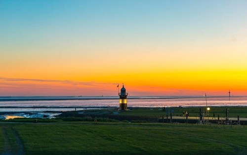 Black and white lighthouse, called 'Kleiner Preusse', stands on the coast of the North Sea under a