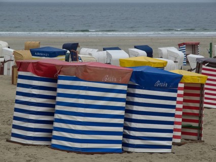 Row of colourful beach chairs with stripe pattern on the beach with a view of the sea, beach chairs