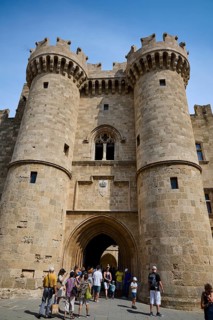 Super wide angle shot, portrait format, tourists enter through a large portal crowned with
