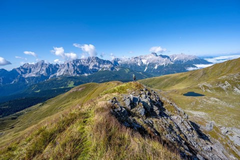 Mountaineers on a hiking trail between green mountain meadows on a mountain ridge, mountain