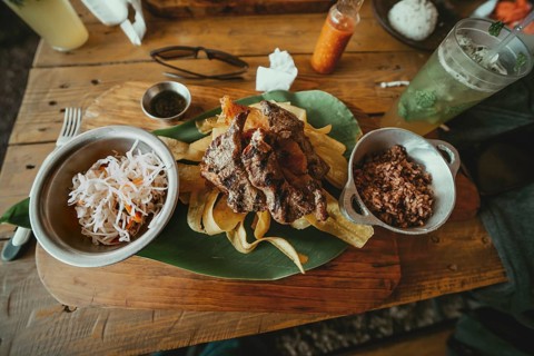 Traditional roast beef with slices of banana and gallopinto served on a wooden table. Wooden table
