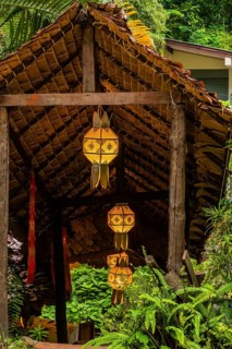 Beautiful oriental lanterns hanging under covered walkway surrounded by lush green foliage in