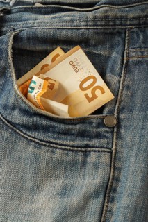 Euro bills coming out of a jeans pocket