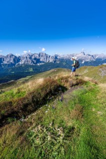 Mountaineers on a hiking trail between green mountain meadows, mountain panorama, view of rocky